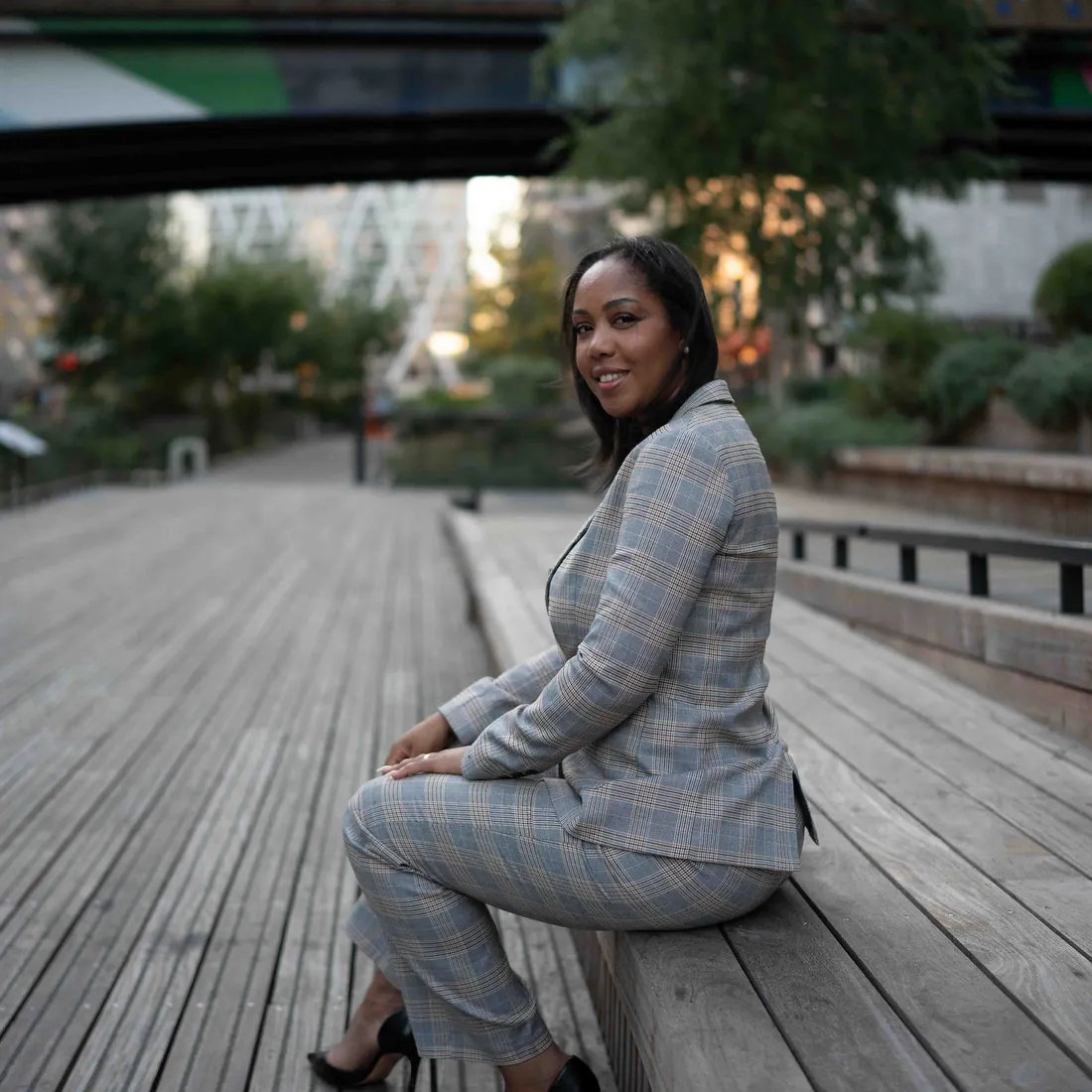 Djany Costa sentada num deck de madeira, com os edifícios de Londres ao fundo